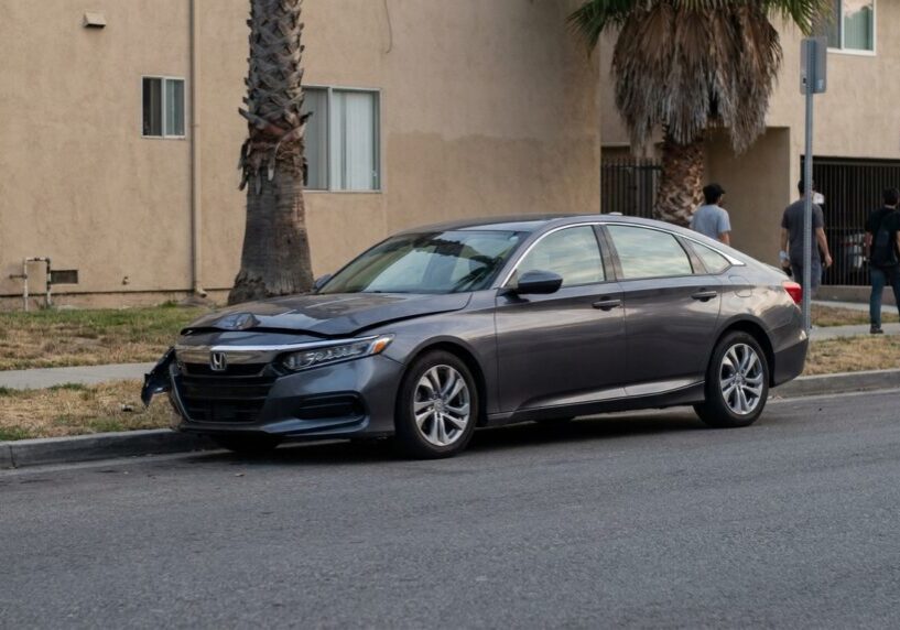 Honda Accord sedan with front-end collision damage parked on urban street